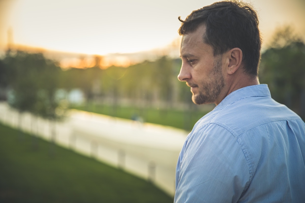 Portrait of handsome middle-aged man in sunmmer morning park. Pensive calm man in casual clothes overgreen nature outdoor.