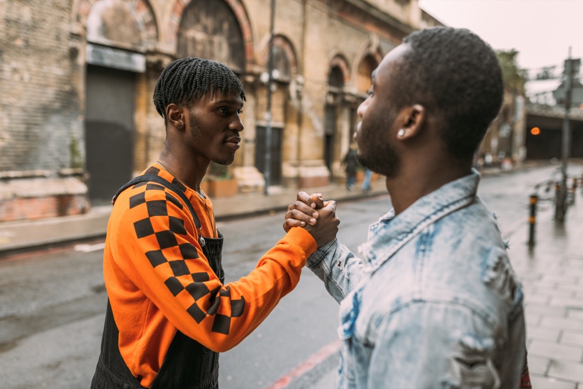 young black man shaking hands on the street