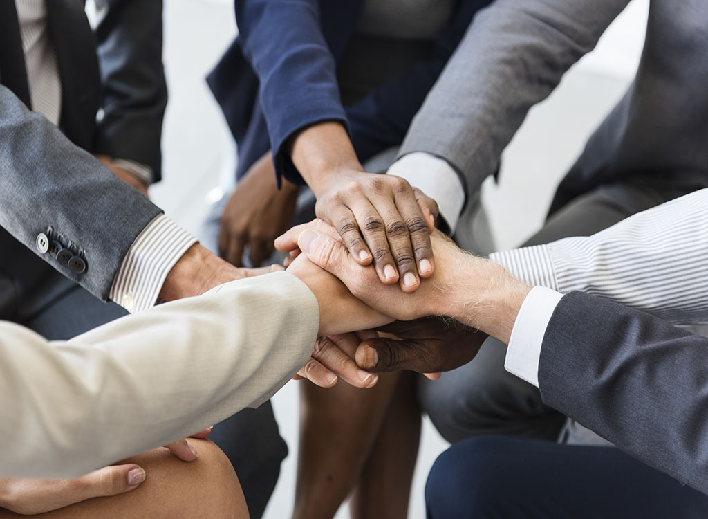 several hands touching in the middle of a circle