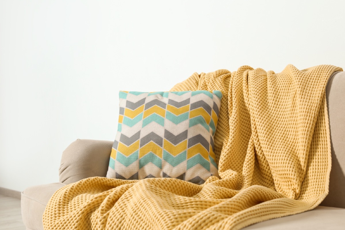 yellow throw blanket and patterned pillow on a couch