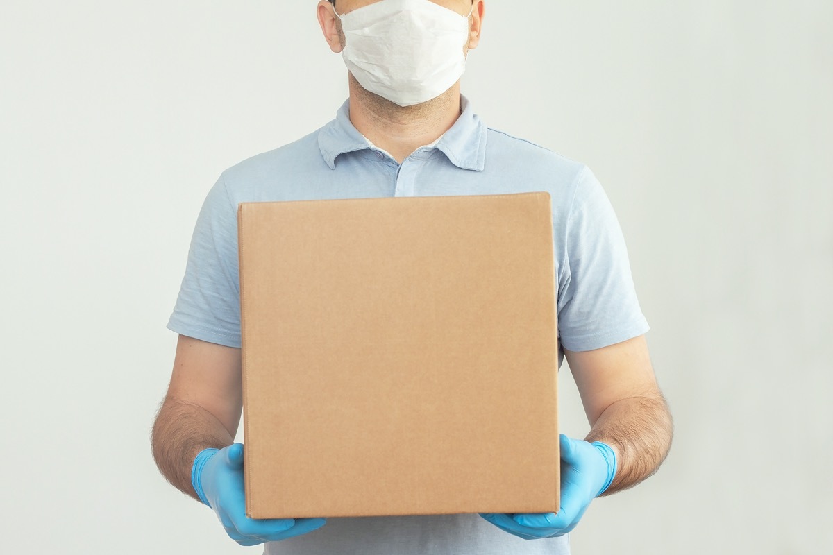 Delivery man holding cardboard boxes in medical rubber gloves and mask. copy space. Fast and free Delivery transport . Online shopping and Express delivery . Quarantine