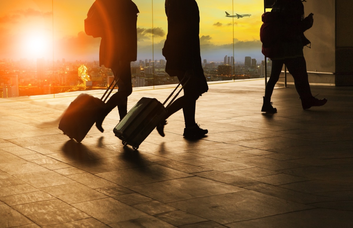 people arriving at the airport early pulling suitcases