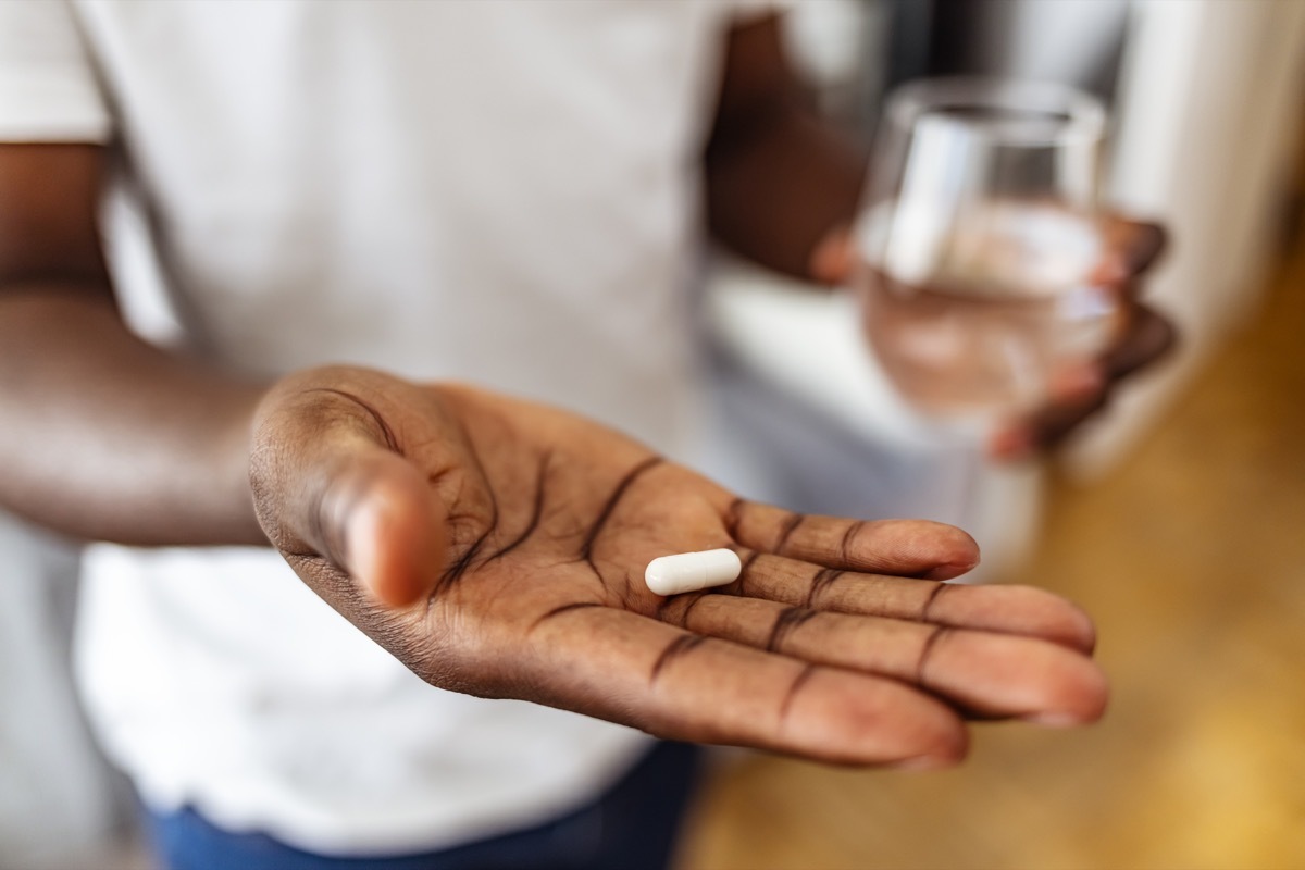 man ready to take a pill while standing at home, copy space