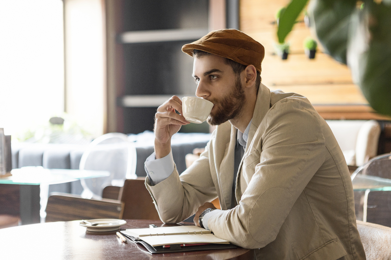 Young man taking notes in cafe drinking coffee