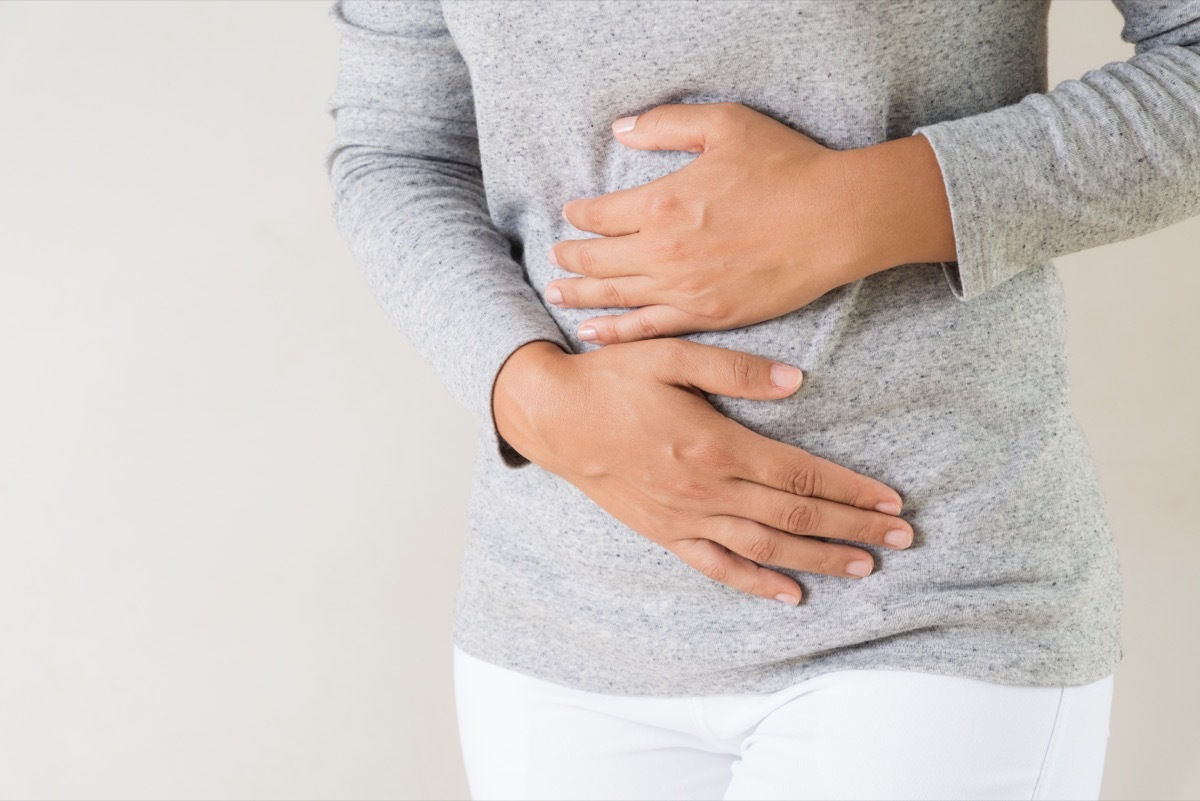 Closeup of a young woman having painful stomachache, clutching her stomach