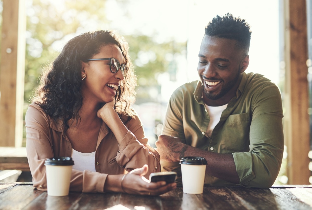 shot of a young couple using a mobile phone together at a cafe