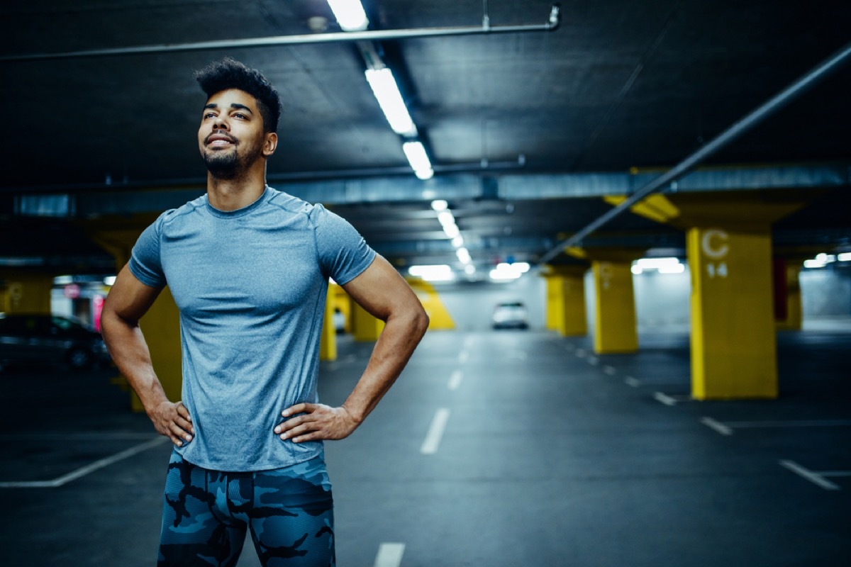 young black man with his hands on his hips in parking lot