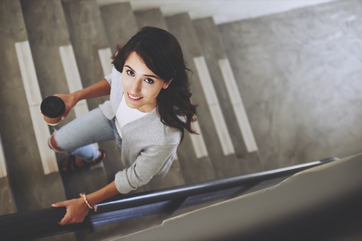 Portrait of lovely brunette walking up the stair, view from above