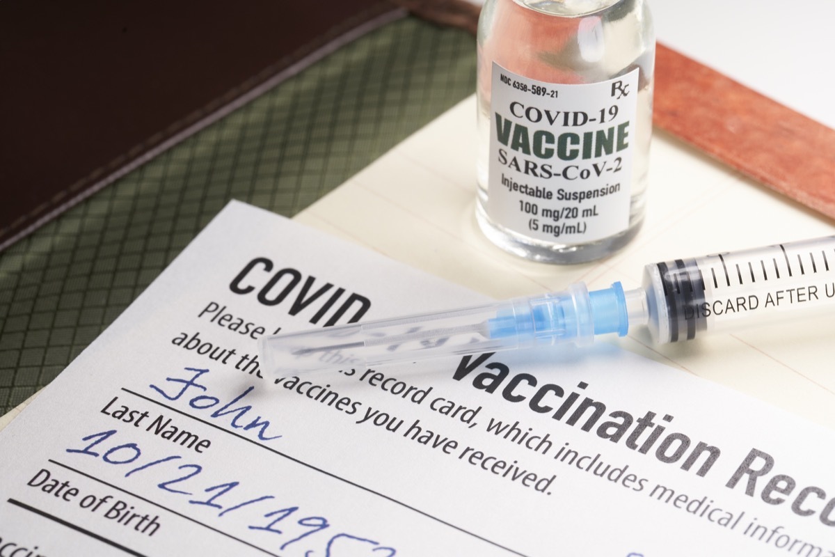 Covid-19 vaccination record card with syringe and vial