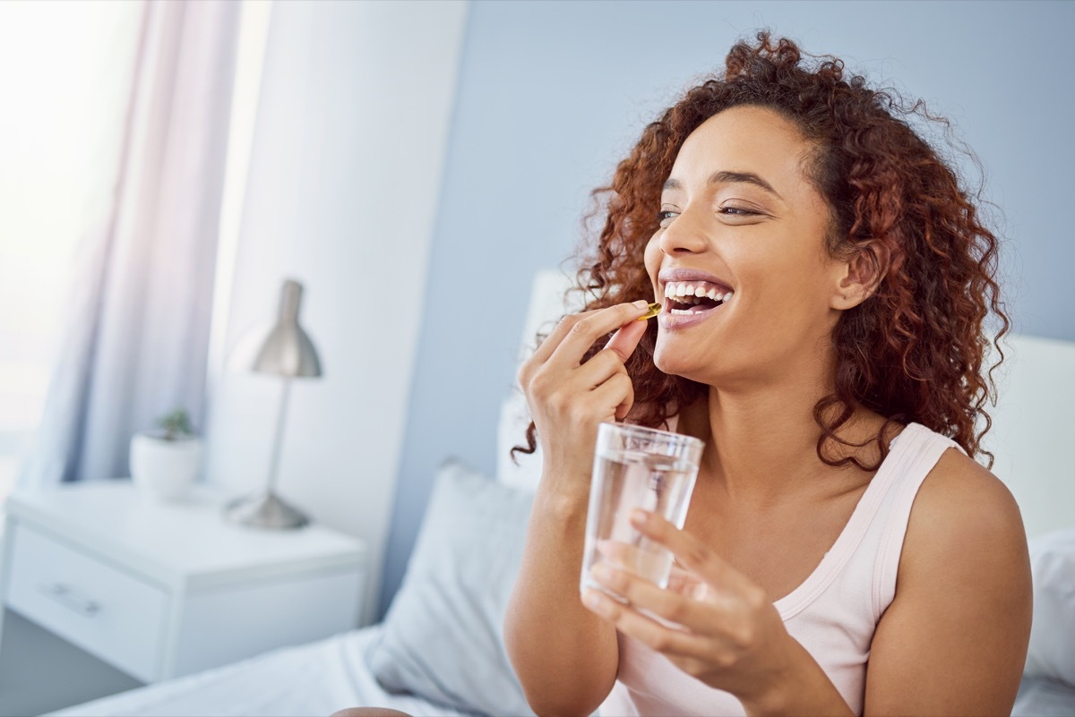 woman taking vitamins with water