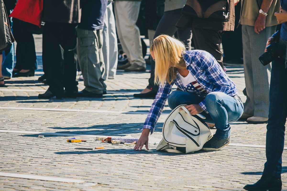 Young woman dropped a white purse and all contents have dropped on the floor