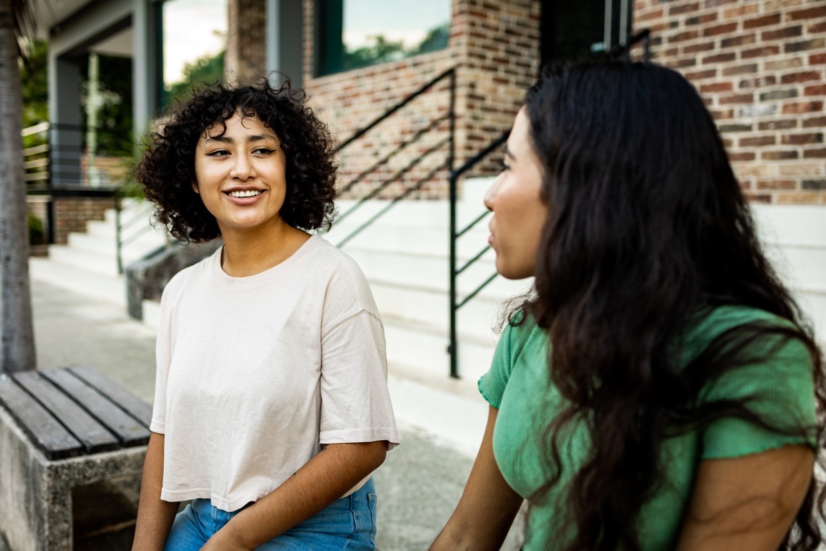 Two young women sitting outdoors and talking