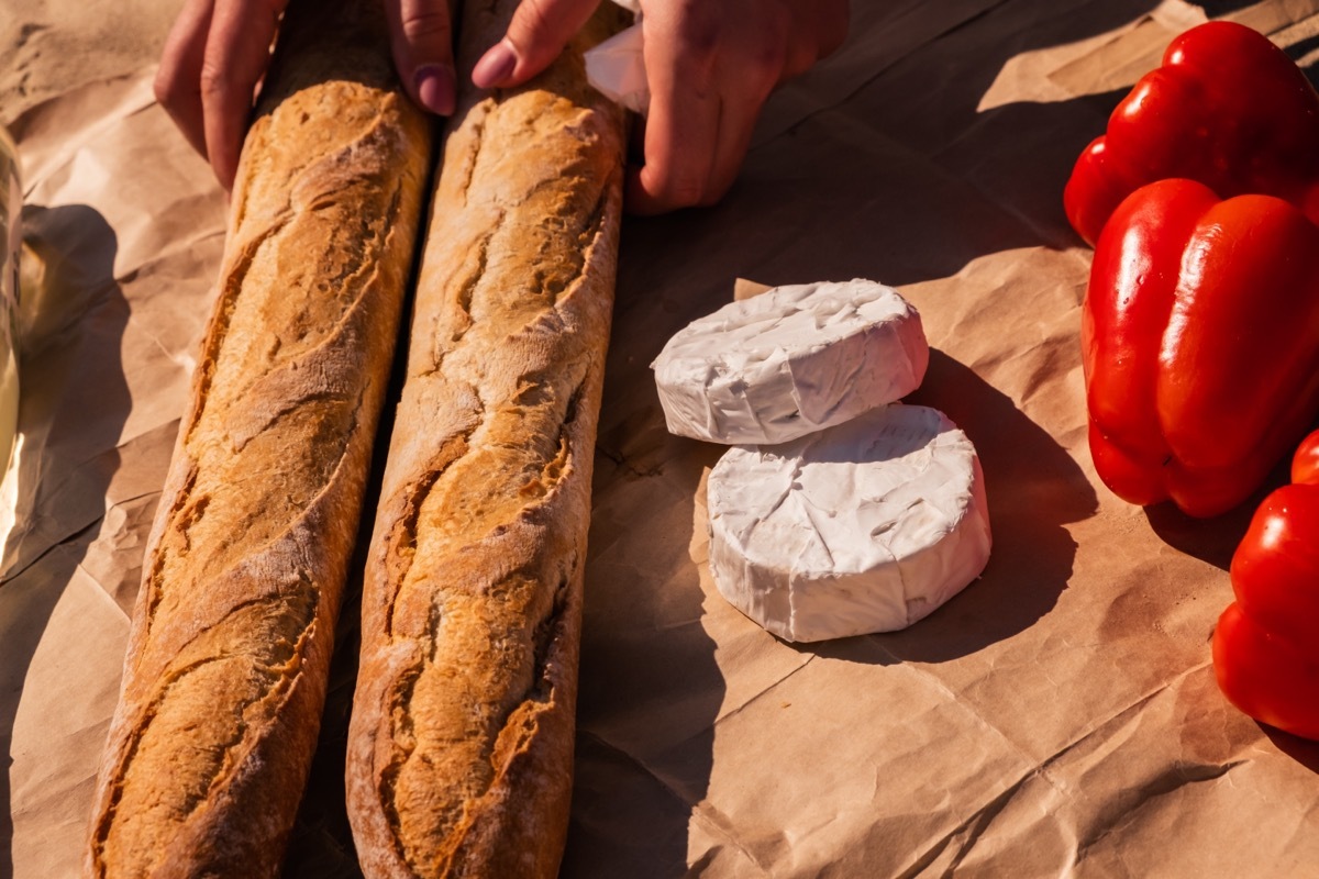 Vegetables, bread, cheese and wine. Picnic in nature. Summer dinner. Crispy bread under the sun. Food layout. Food for summer advertising.