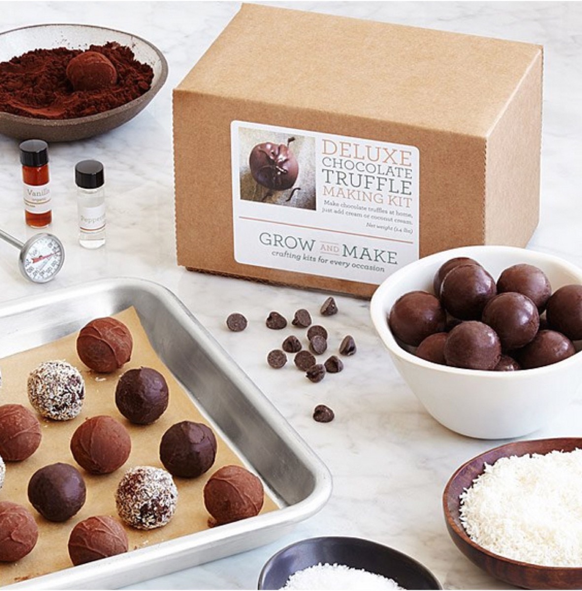 pan of chocolate truffles next to a white bowl of truffles and brown cardboard box