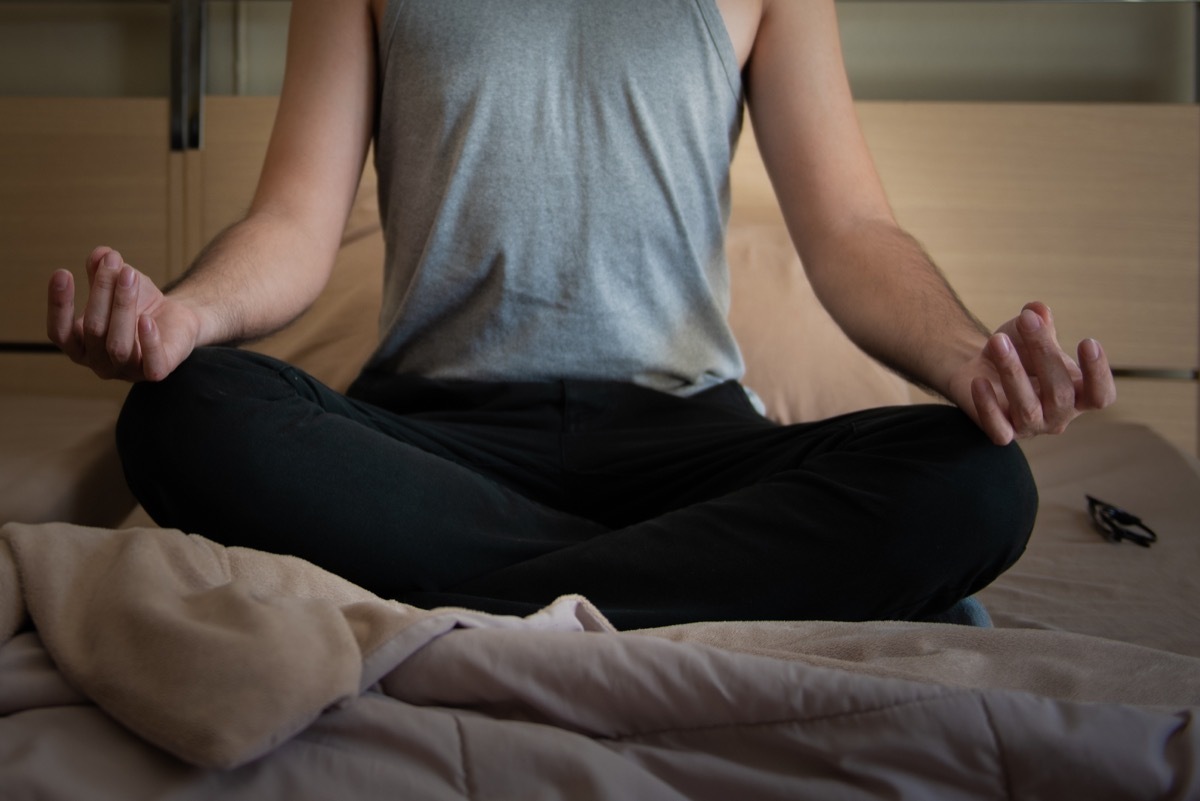 Man meditating on bed before going to sleep.