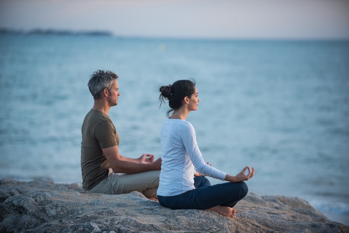 couple doing yoga at dawn on a beach