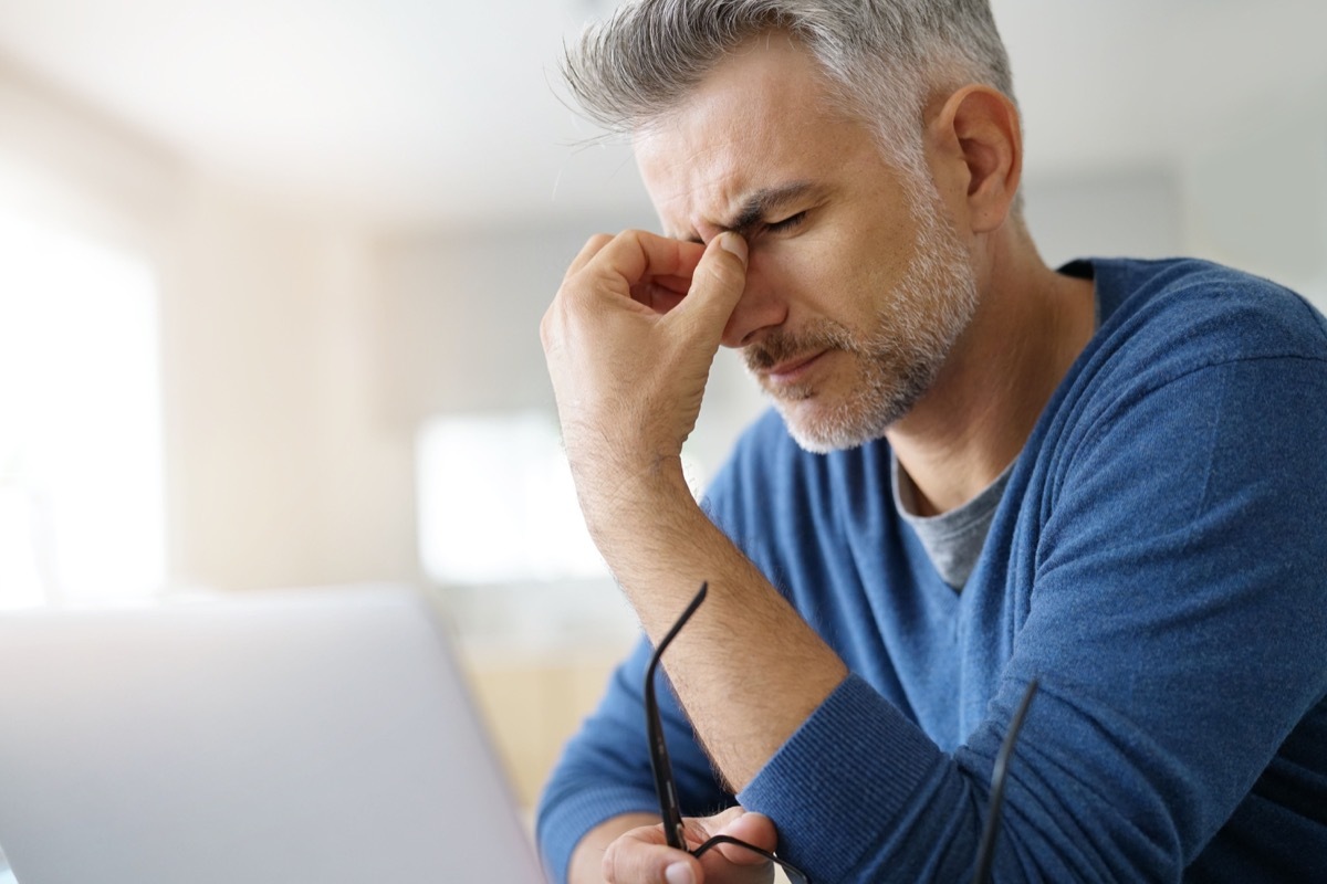 Stressed man with a pressure headache between eyes