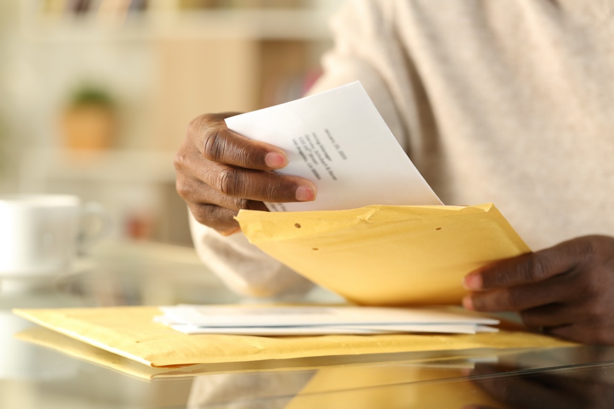 man hands opening a padded envelope with letter on a desk at home