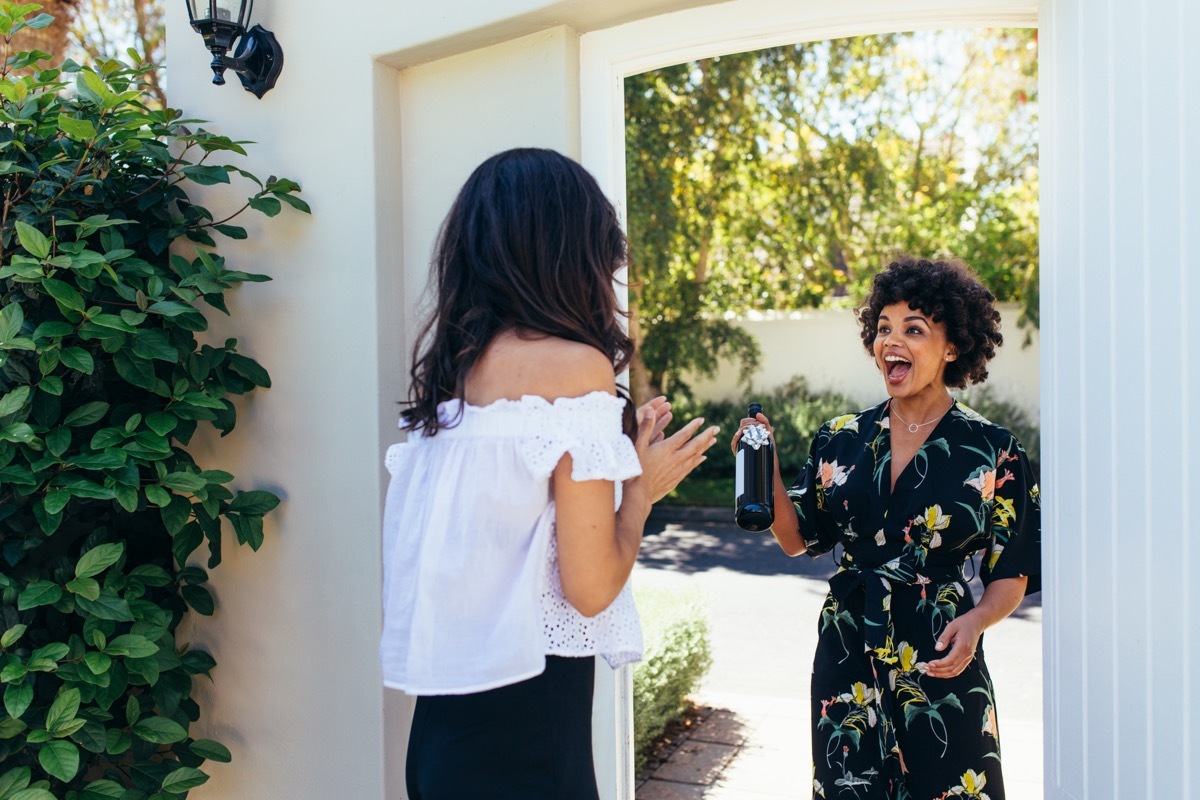 Woman giving host a bottle of wine upon entering home