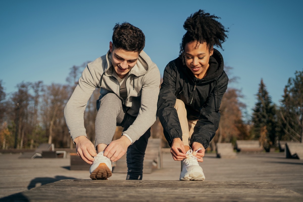 man and woman adjusting sneakers before a walk