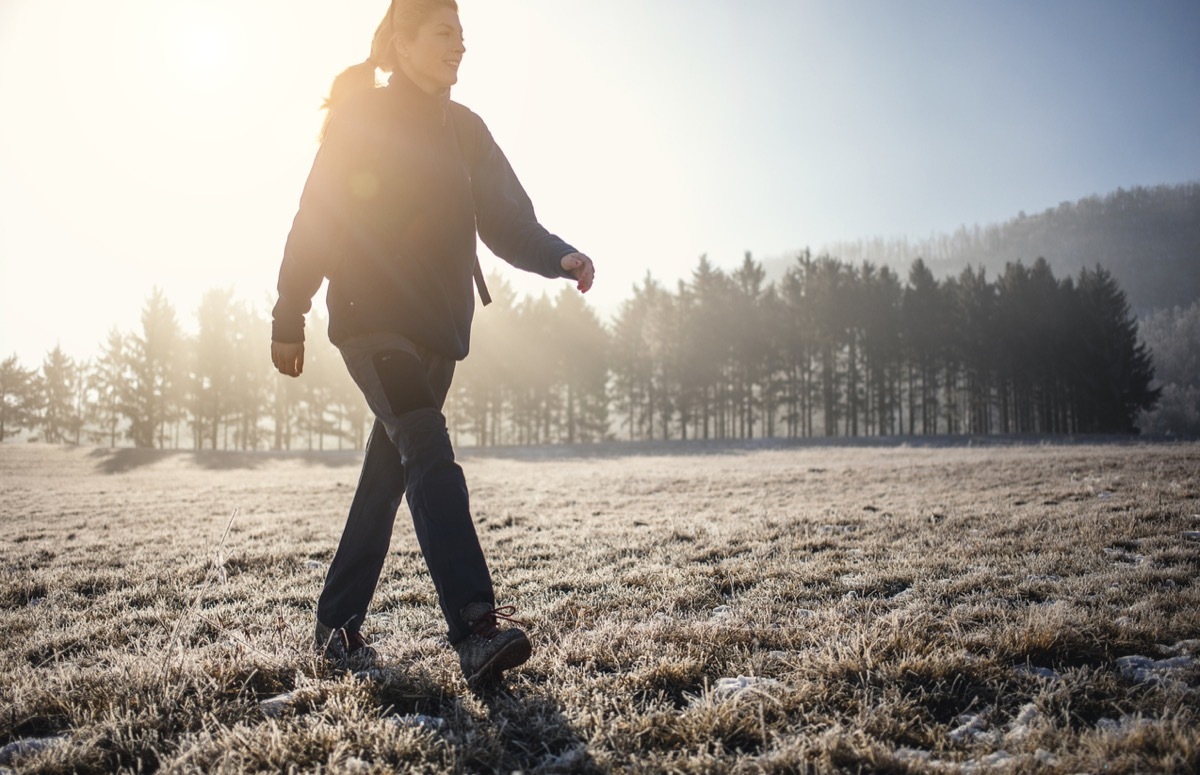 Female Hiker Walking Across the Forrest Field in Winter