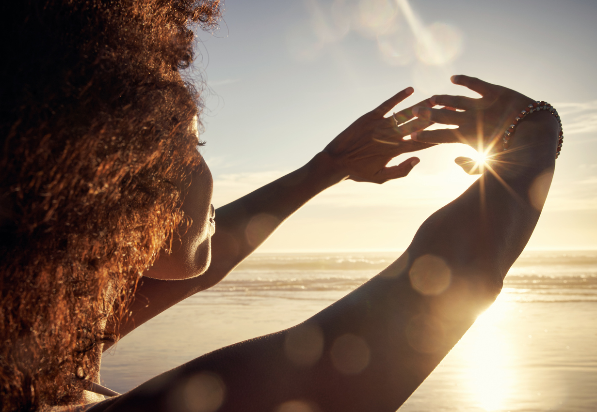 Woman blocking the sunlight with her hands at the beach.