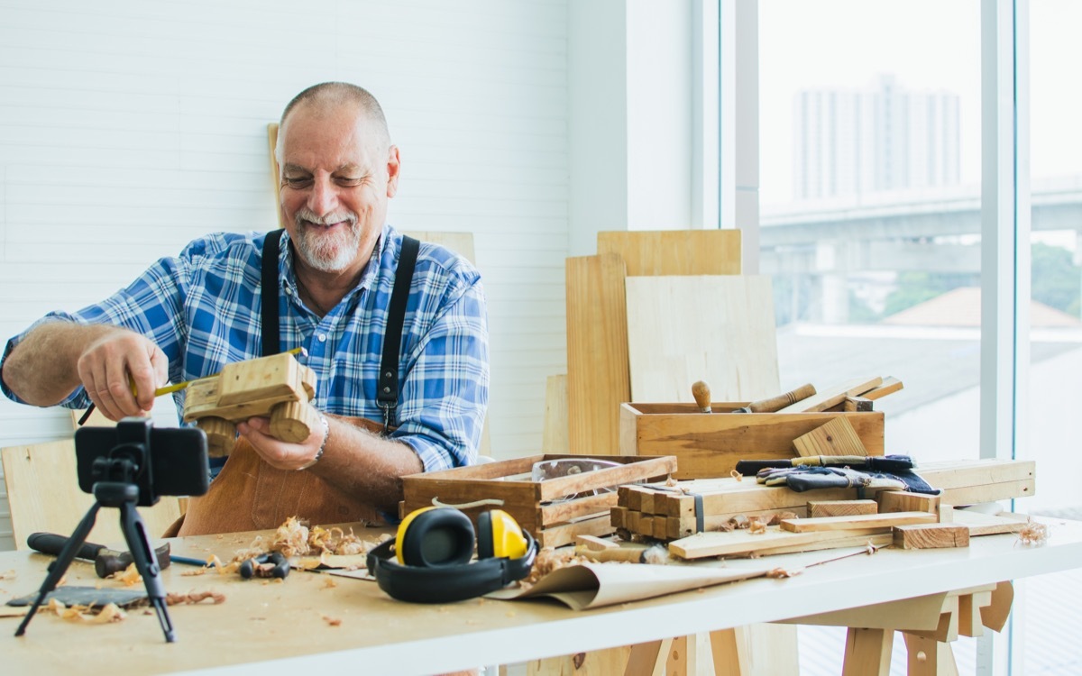 older man making diy furniture and taking photos