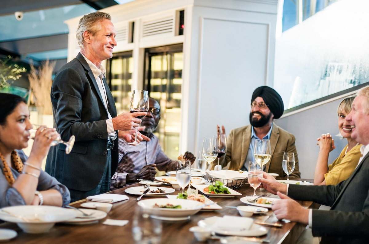 A man standing up at a business dinner