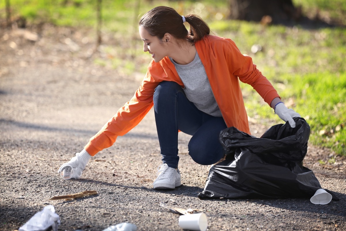 girl picking up litter in park small acts of kindness