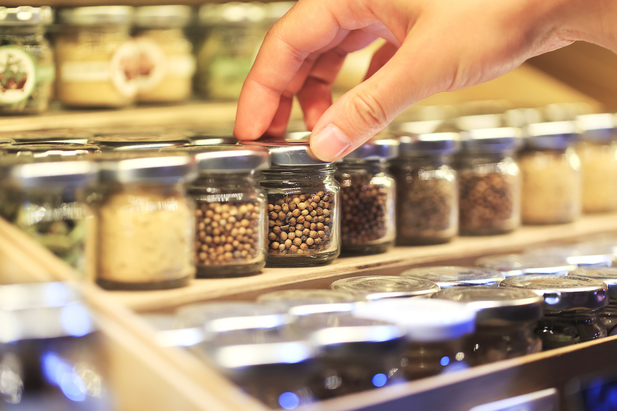 closeup woman's hand picking jar of spices