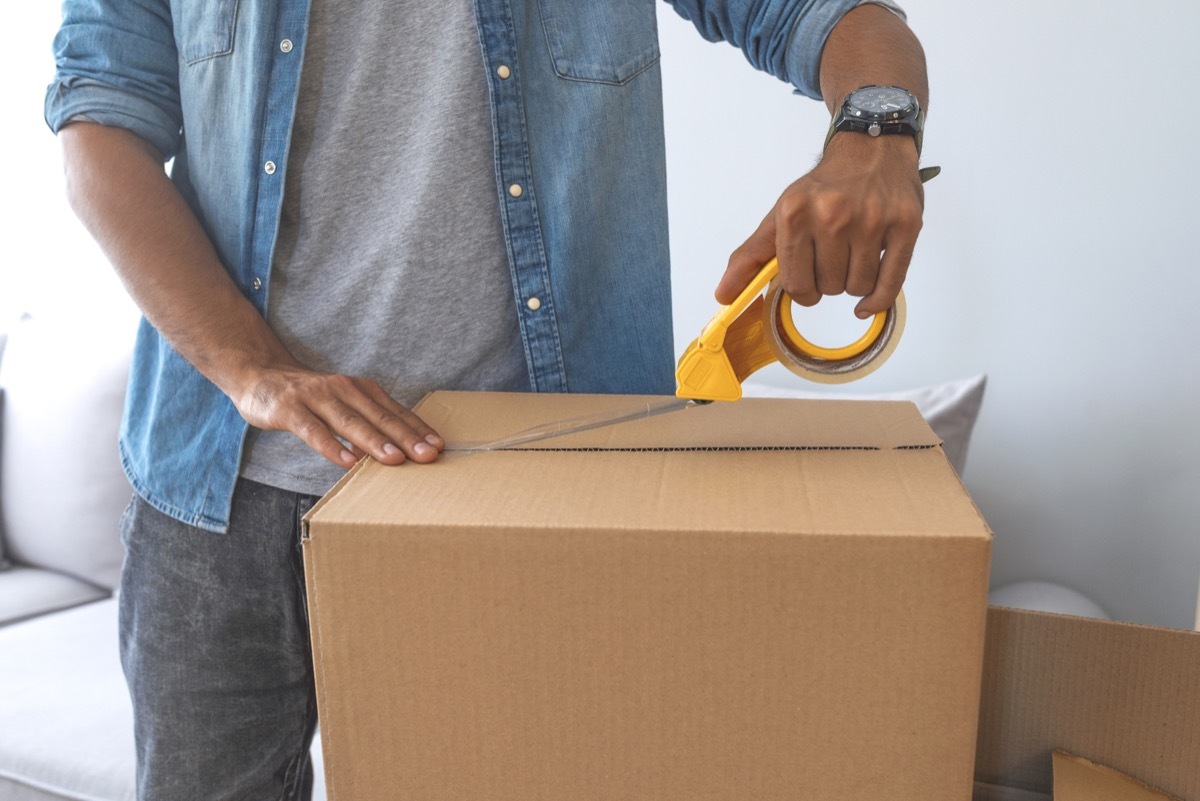 close up of male hand packing cardboard box, concept moving house. House moving concept. Happy young couple moving into new apartment with packaging boxes