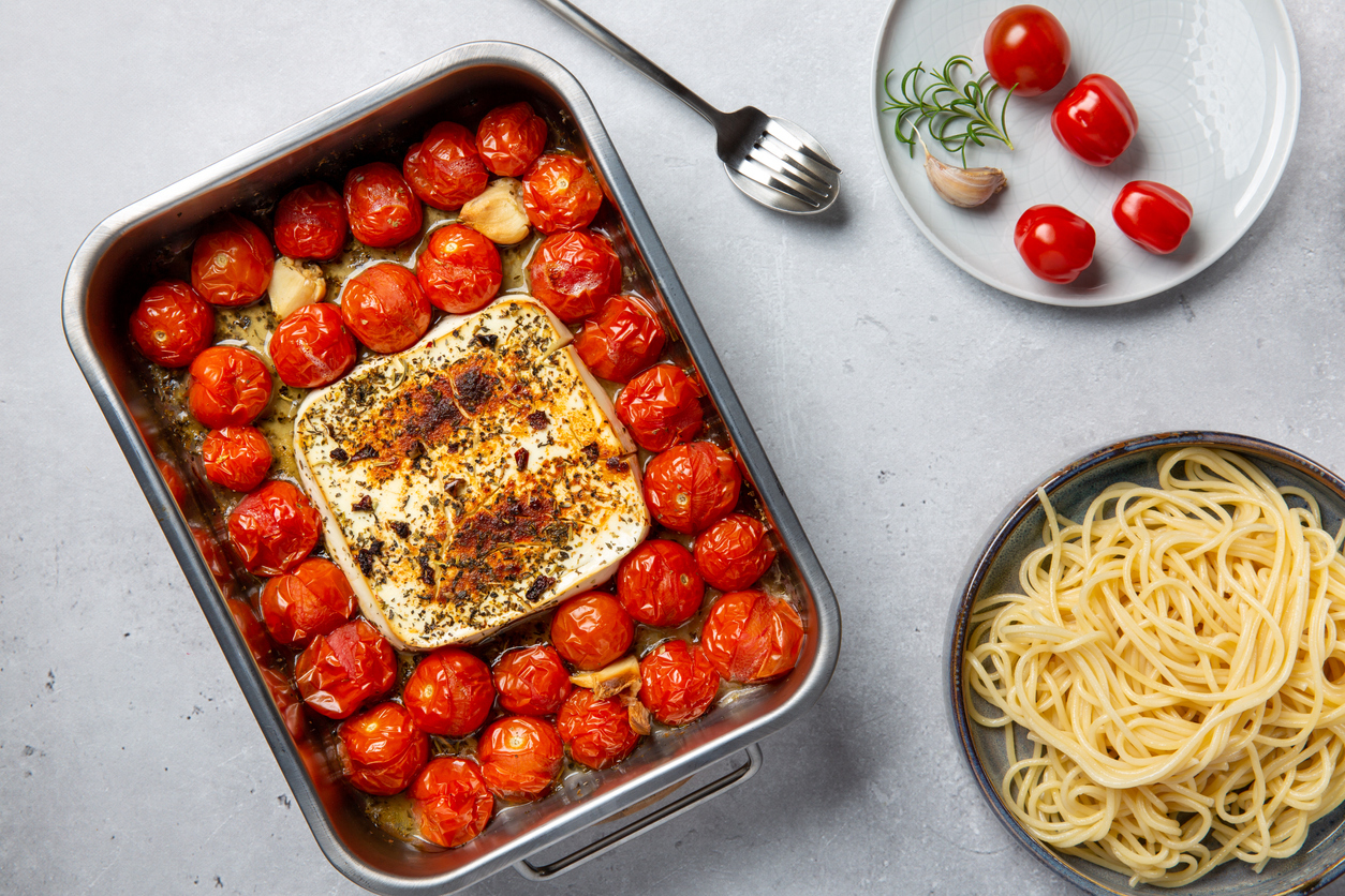 Oven baked feta pasta made of cherry tomatoes, feta cheese, garlic and herbs. Fetapasta on gray background. 