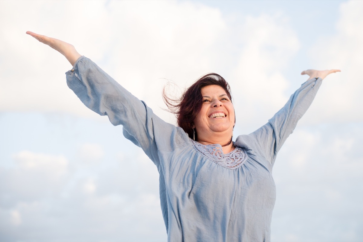 excited older latina woman throwing up her hands