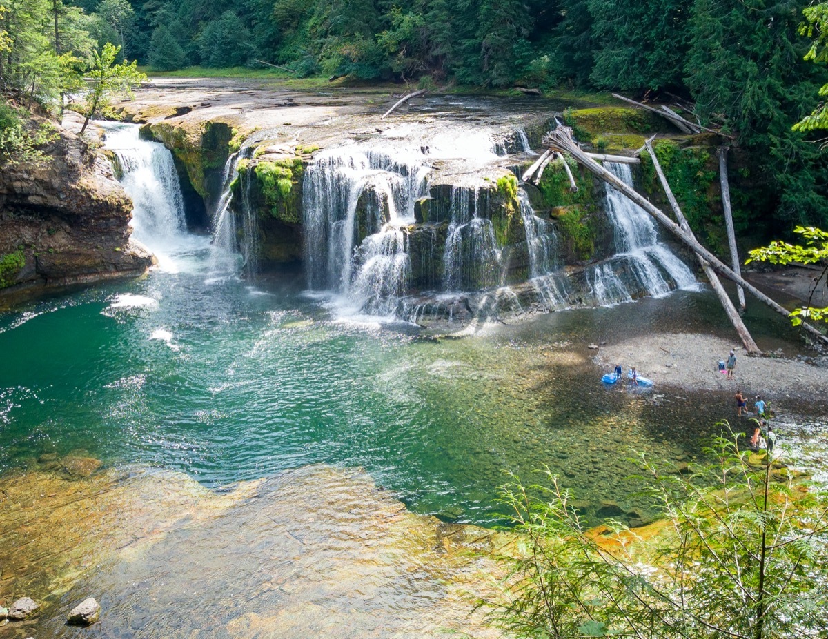 people swimming in turquoise waterfall