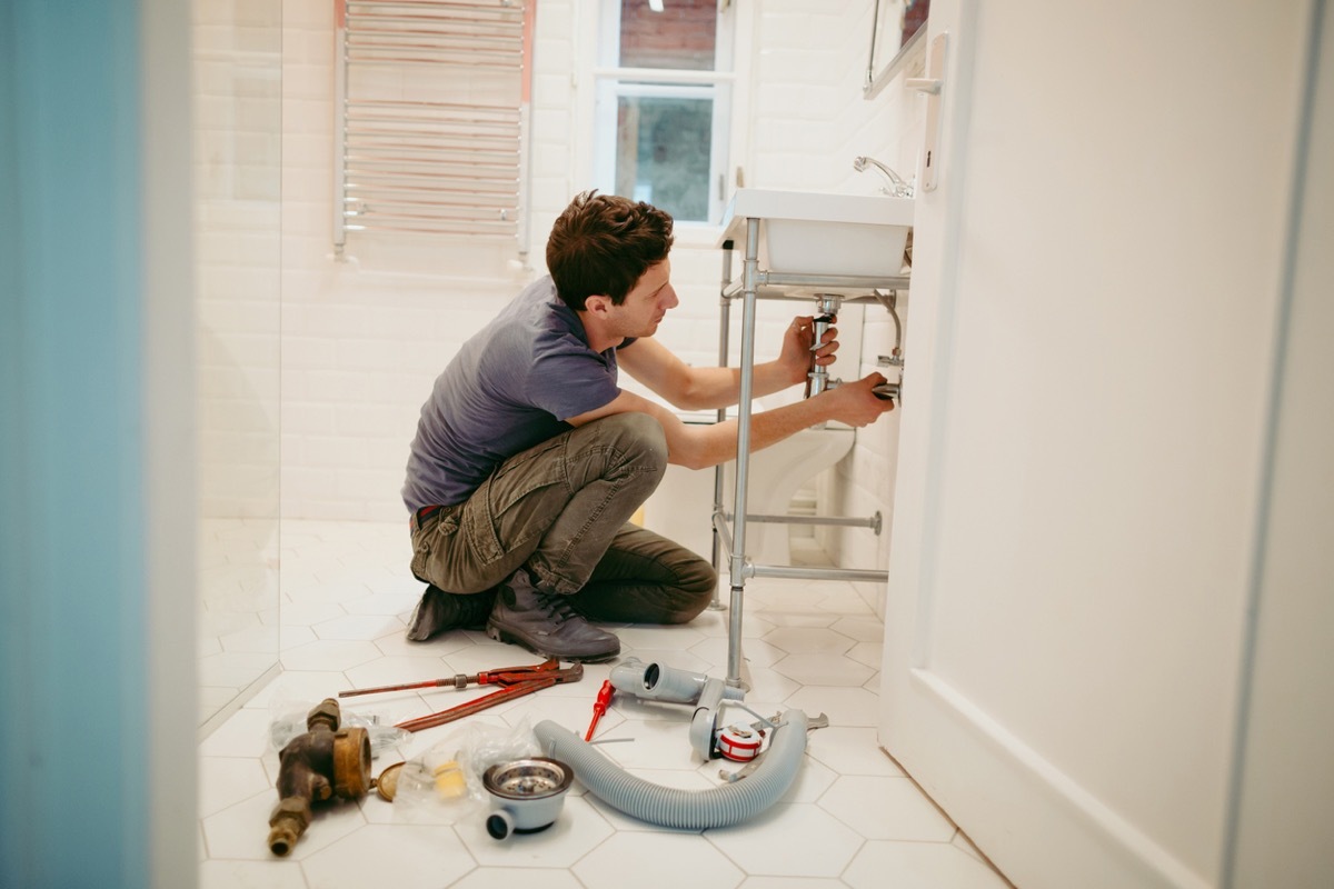 Young man fixing a leak under the bathroom sink