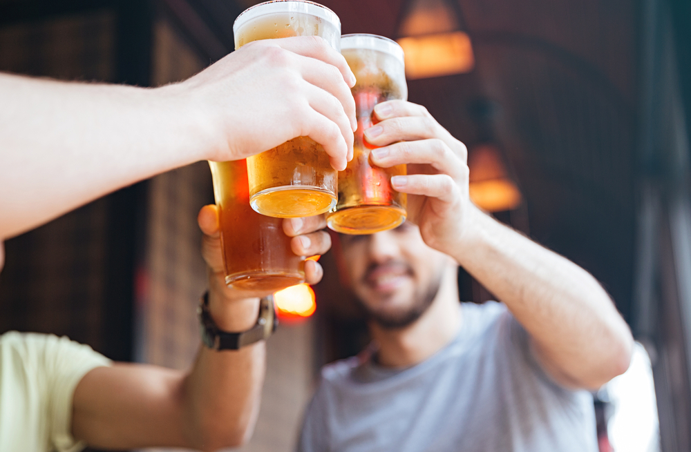 A group of young men cheersing their beers in a bar