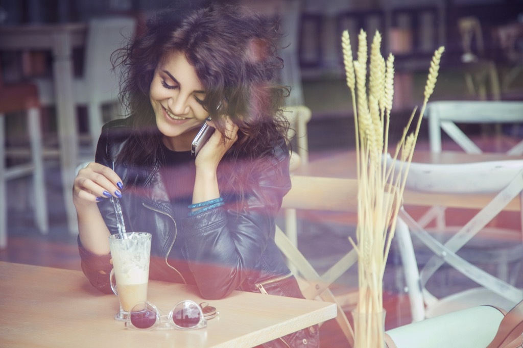 woman on phone in cafe, where she can strip away stress bad habits