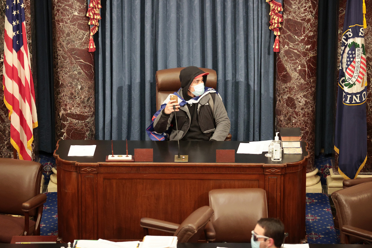 A protester sits in the Senate Chamber on January 06, 2021 in Washington, DC. Congress held a joint session today to ratify President-elect Joe Biden's 306-232 Electoral College win over President Donald Trump. Pro-Trump protesters have entered the U.S. Capitol building after mass demonstrations in the nation's capital.