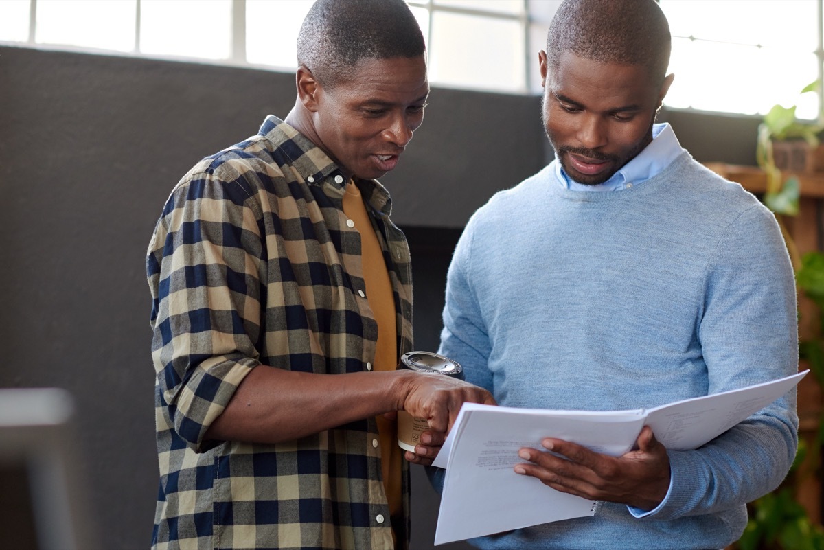 two middle-aged black men talking at work