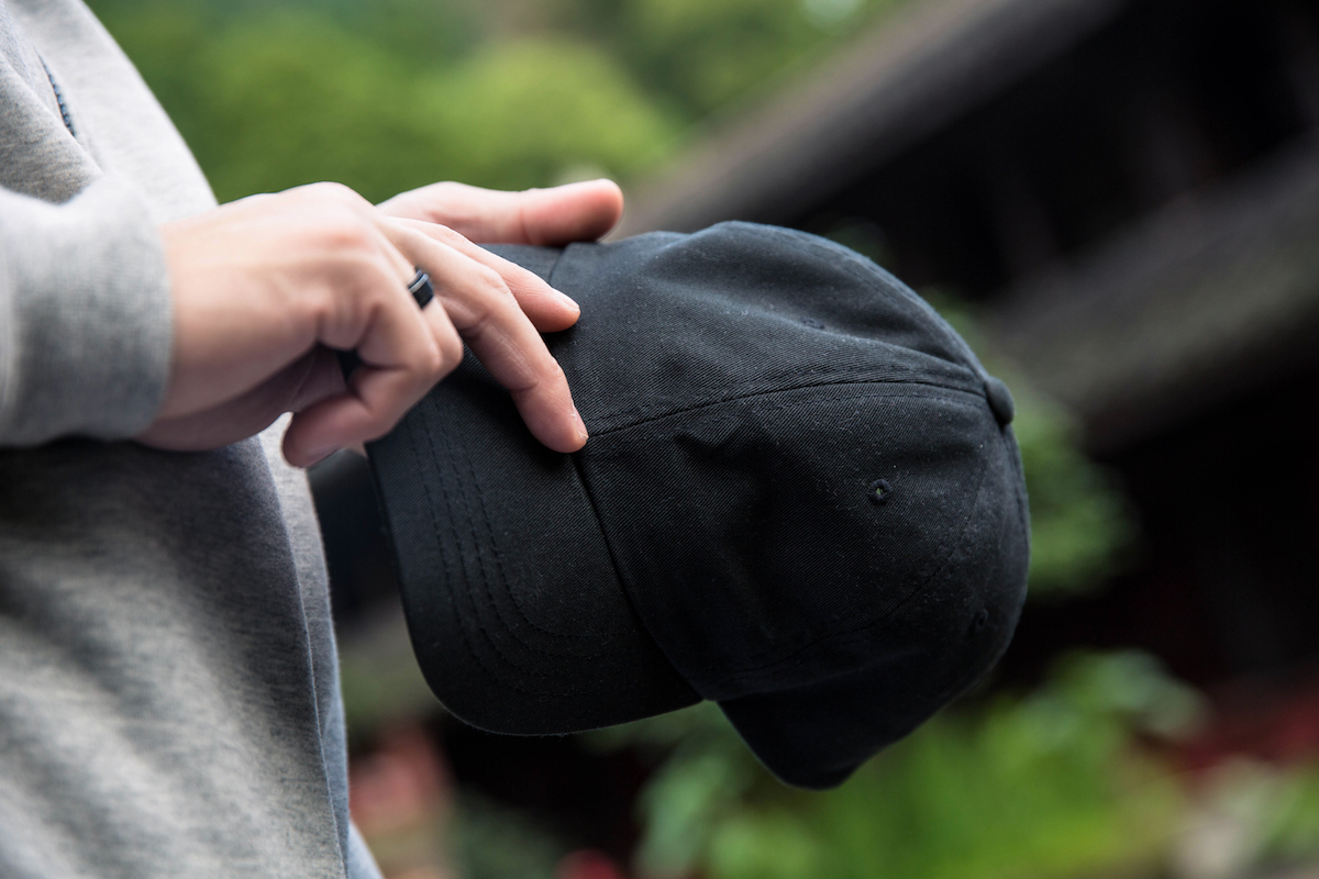 closeup of man holding black baseball hat