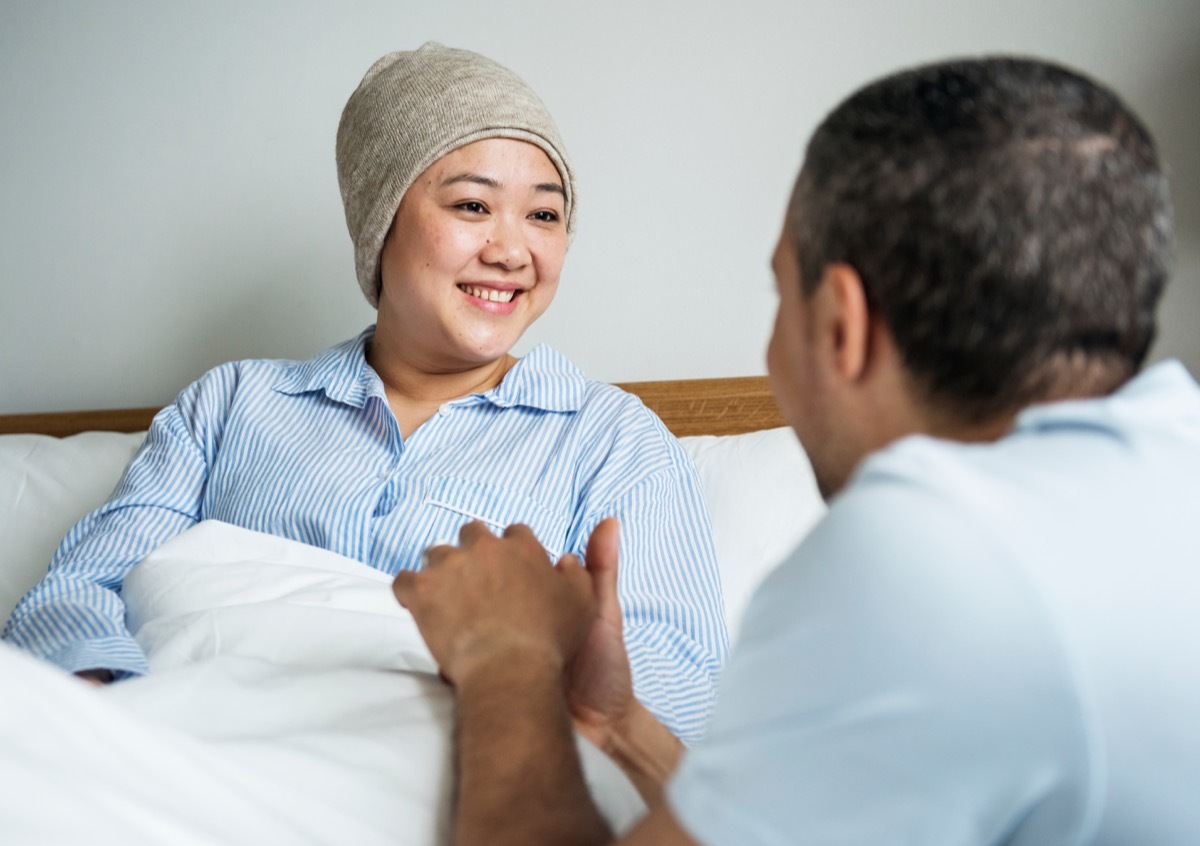 Woman with cancer talking to husband in hospital bed