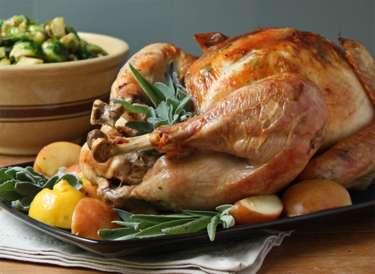 roasted whole turkey on pan with potatoes and halved lemon, crispy skin and sage butter on turkey