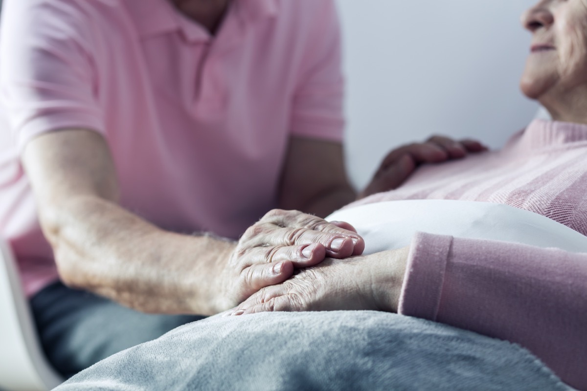 Man holding hand of dying woman