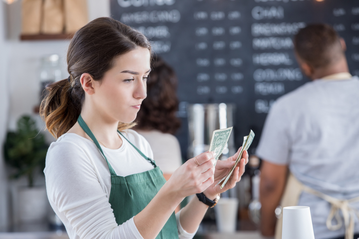 A server counting their tips with a disappointed look on their face