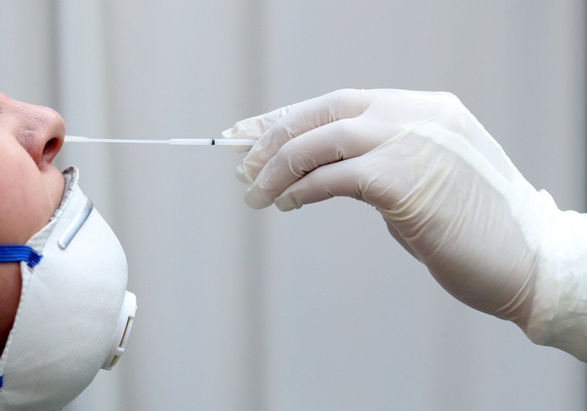 Medical staff member with mask, rubber gloves and protective equipment performs Coronavirus nasal swabs to patient