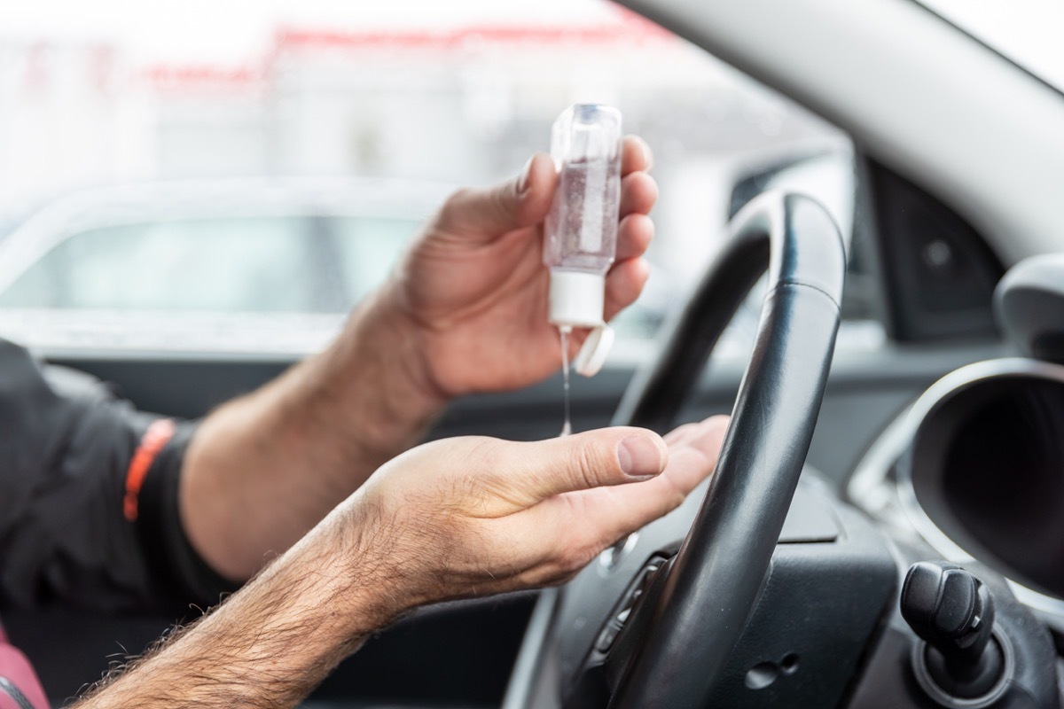 Man using hand sanitizer while sitting in car