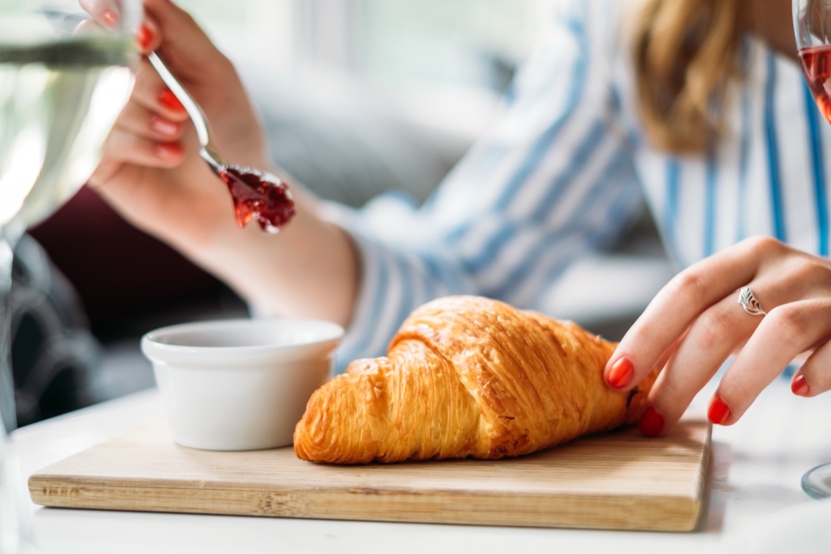 woman eating croissant with jam