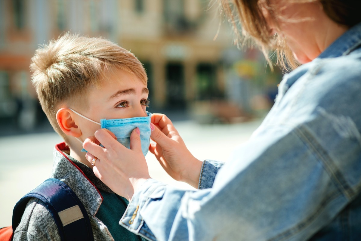 Mother puts a safety mask on her son's face.