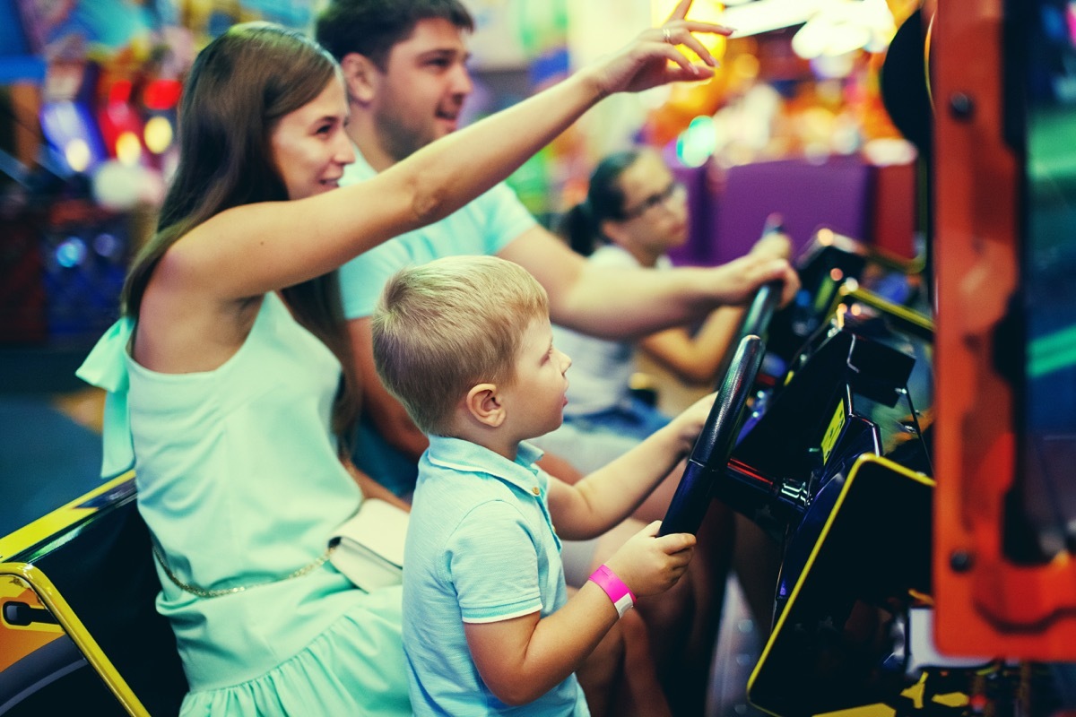 Family playing a driving game at an arcade