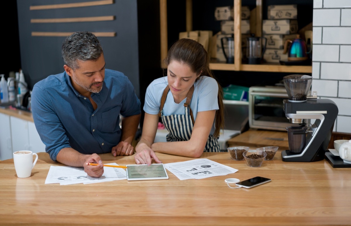 Business owner doing to the books at a cafe with a waitress